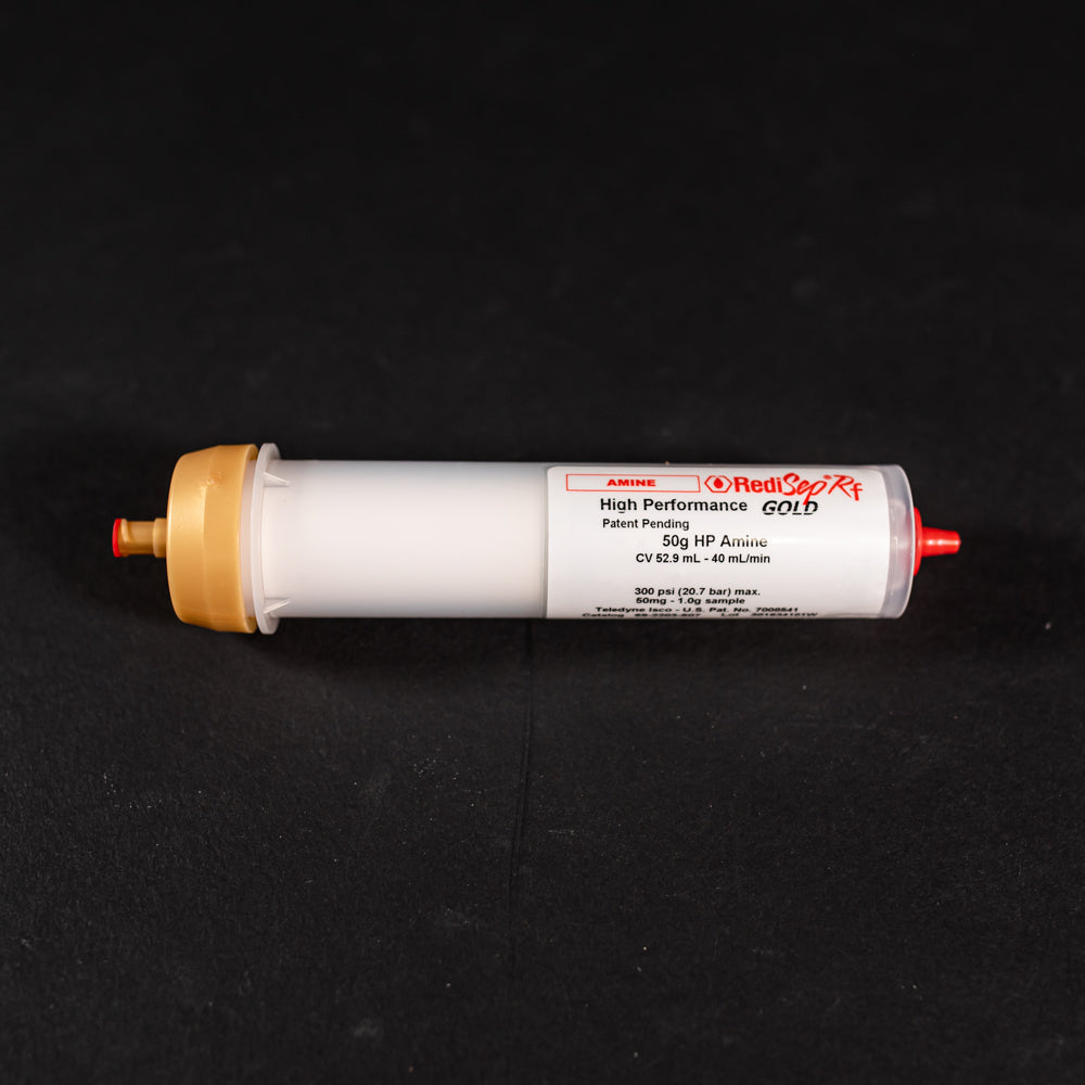 A small white tube with gold and red caps displayed on a black background, creating a striking visual contrast between the two elements.