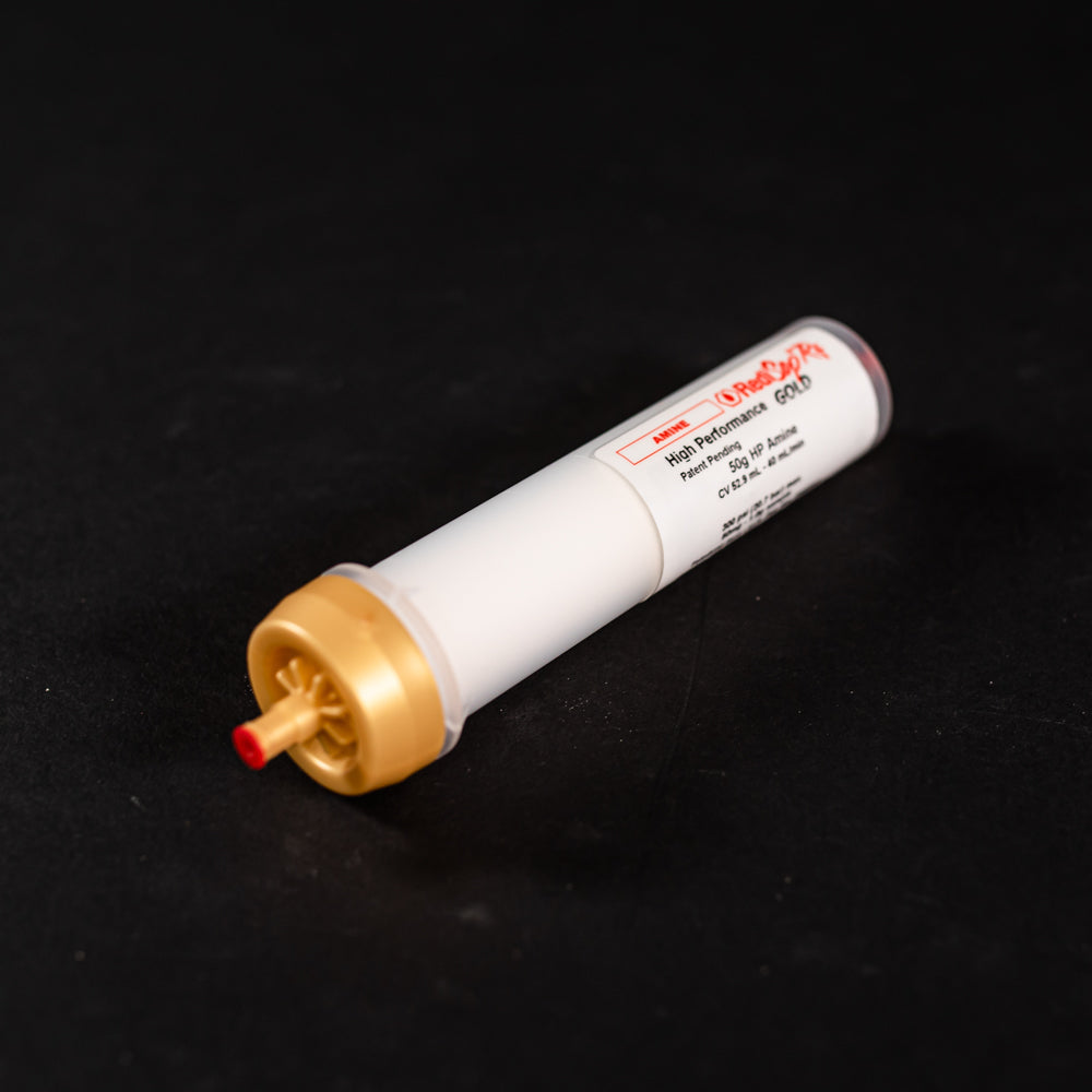A small white tube with gold and red caps displayed on a black background, creating a striking visual contrast between the two elements.