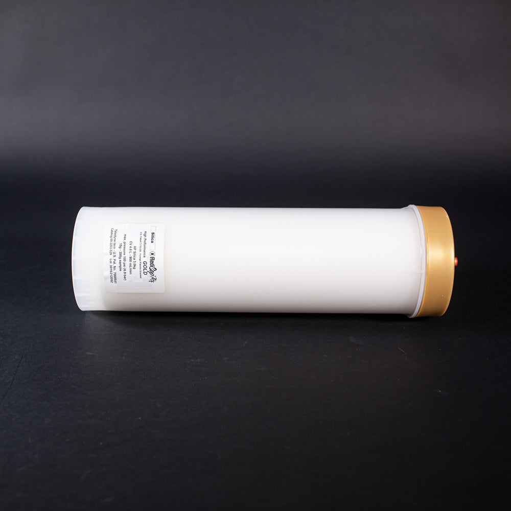 A small white tube with gold and red caps displayed on a black background, creating a striking visual contrast between the two elements.