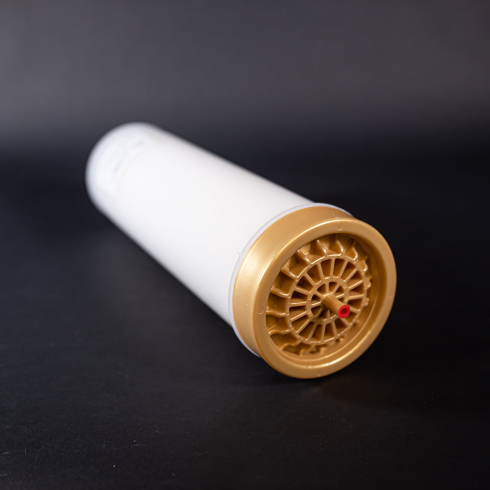 A small white tube with gold and red caps displayed on a black background, creating a striking visual contrast between the two elements.