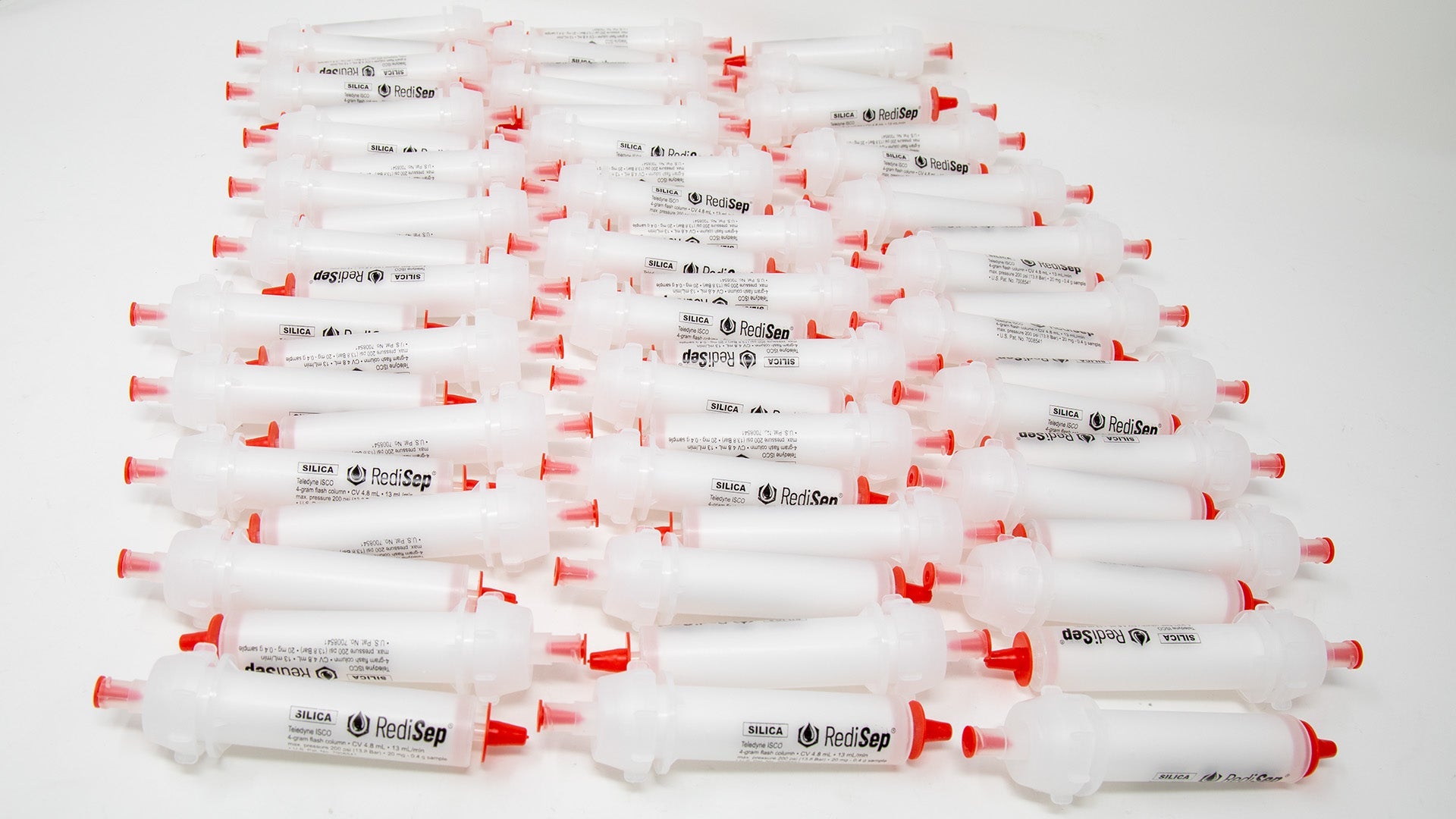 A group of plastic tubes with red caps, positioned side by side, emphasizing their contrasting colors and forms.