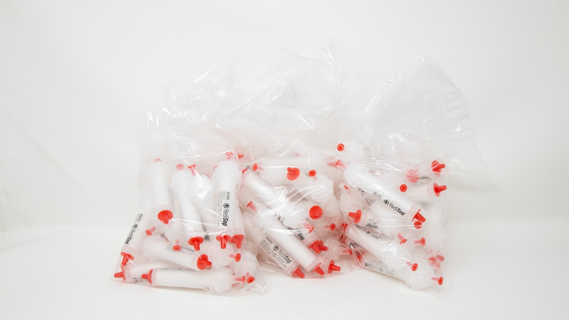 A group of plastic tubes with red caps, positioned side by side, emphasizing their contrasting colors and forms.
