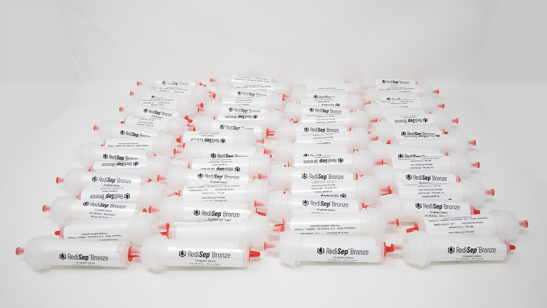 A group of plastic tubes with red caps, positioned side by side, emphasizing their contrasting colors and forms.