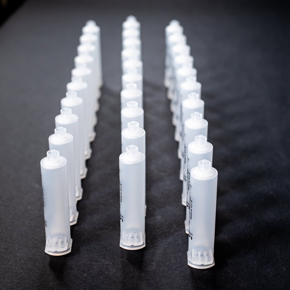 A set of small clear plastic cartridges displayed on a black background, creating a striking visual contrast between the two elements.